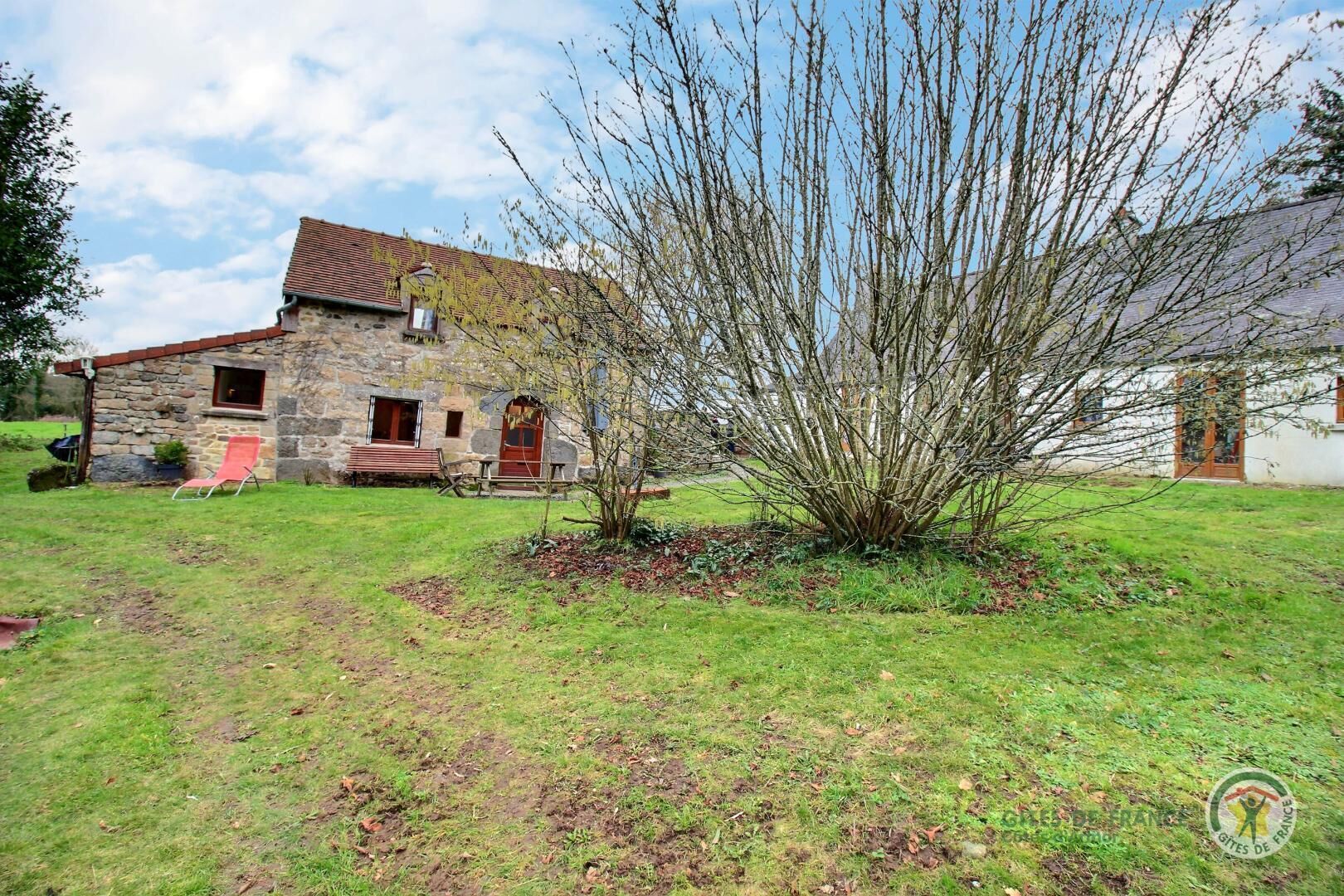 A stone house with a red door and a small garden area.