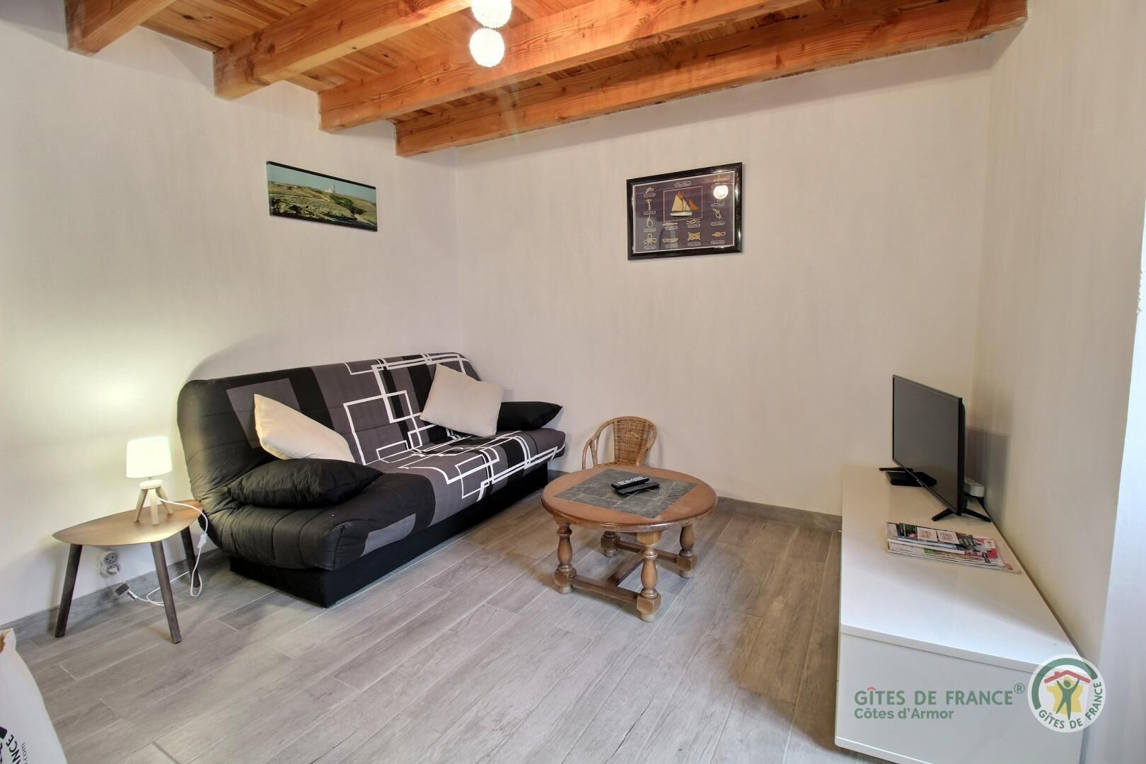 Un salon meublé comprenant un canapé, une petite table, une chaise, une lampe et un téléviseur.