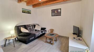 Un salon meublé comprenant un canapé, une petite table, une chaise, une lampe et un téléviseur.
