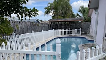 Una piscina al aire libre, sombrillas, sillones reclinables de piscina