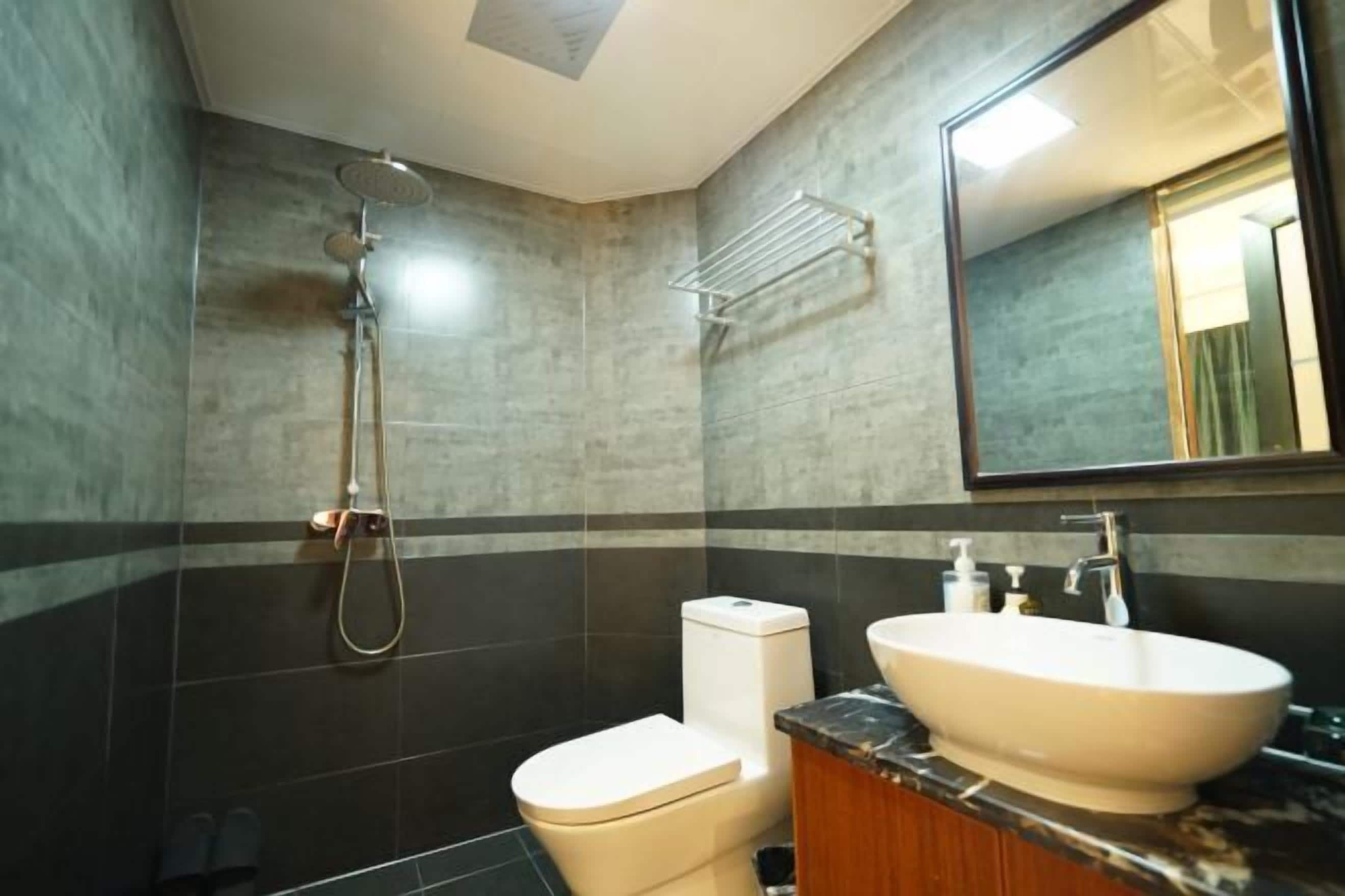 A modern bathroom with a shower, toilet, and sink.