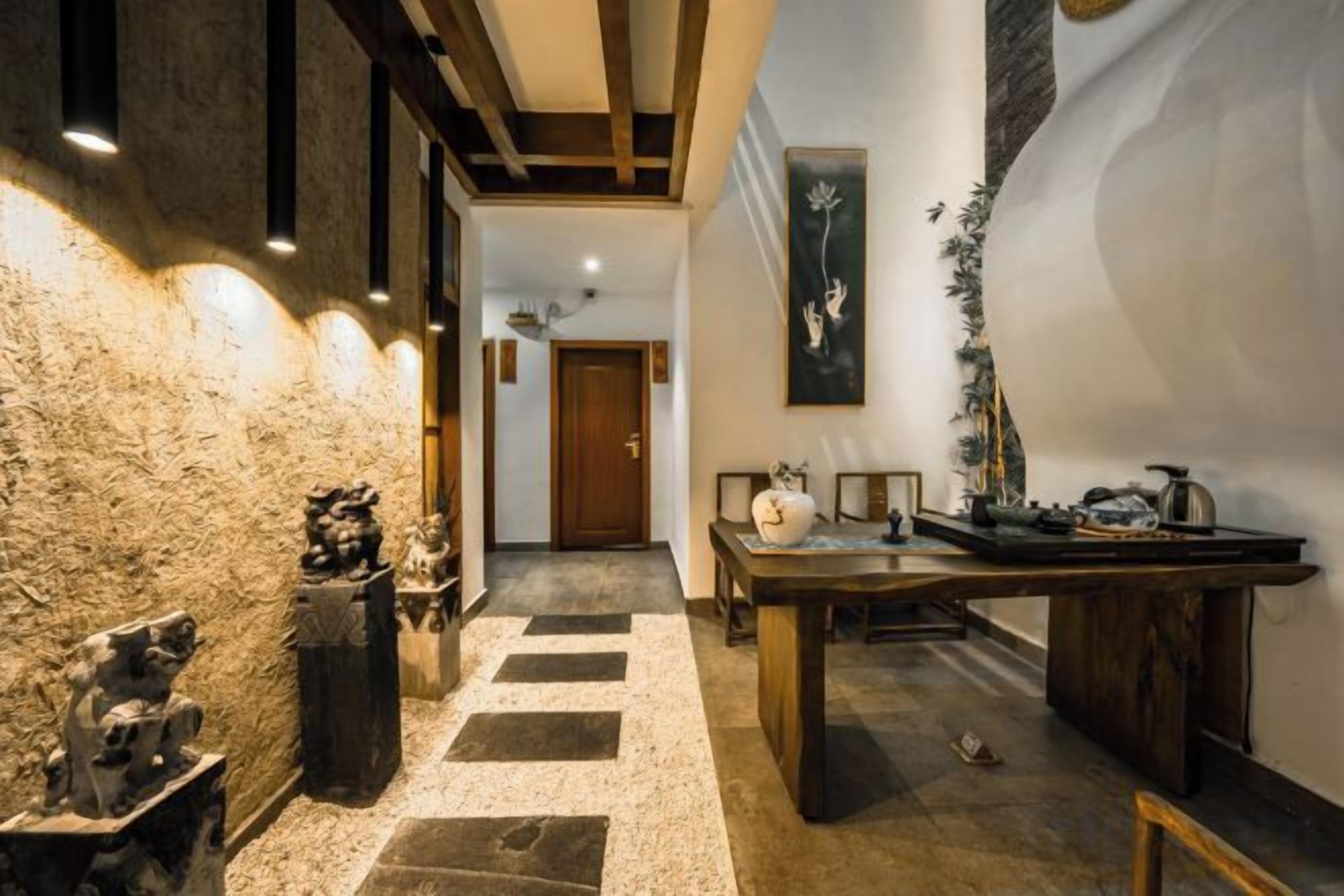Un couloir avec un mur en pierre, une table en bois et une porte au fond.