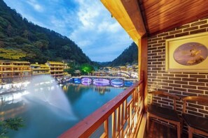 Enjoy a peaceful riverside retreat with a balcony overlooking the calm river and lush green hills.