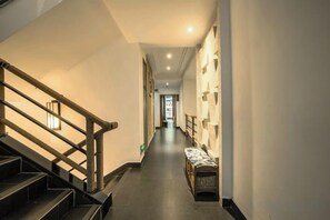 A hallway with a staircase on the left, a bench on the right, and a door at the end. - Fenghuang Fanyin Zhenpin Inn (Fenghuang County)