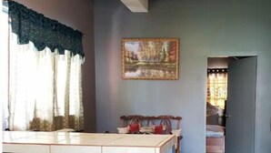 Una cocina con barra, sillas de madera, un ventilador de techo y un cuadro en la pared.