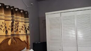 Un dormitorio con cama, armario, televisor y aire acondicionado.