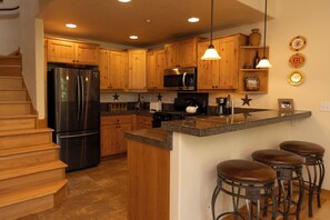 Enjoy cooking in this well-equipped kitchen with a central island, microwave, stove, and refrigerator.