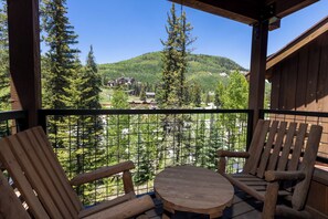 Enjoy a mountain view from this balcony with two chairs and a small table.