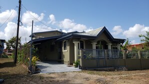 A residential house with a front porch, a fenced yard, and a clear sky.