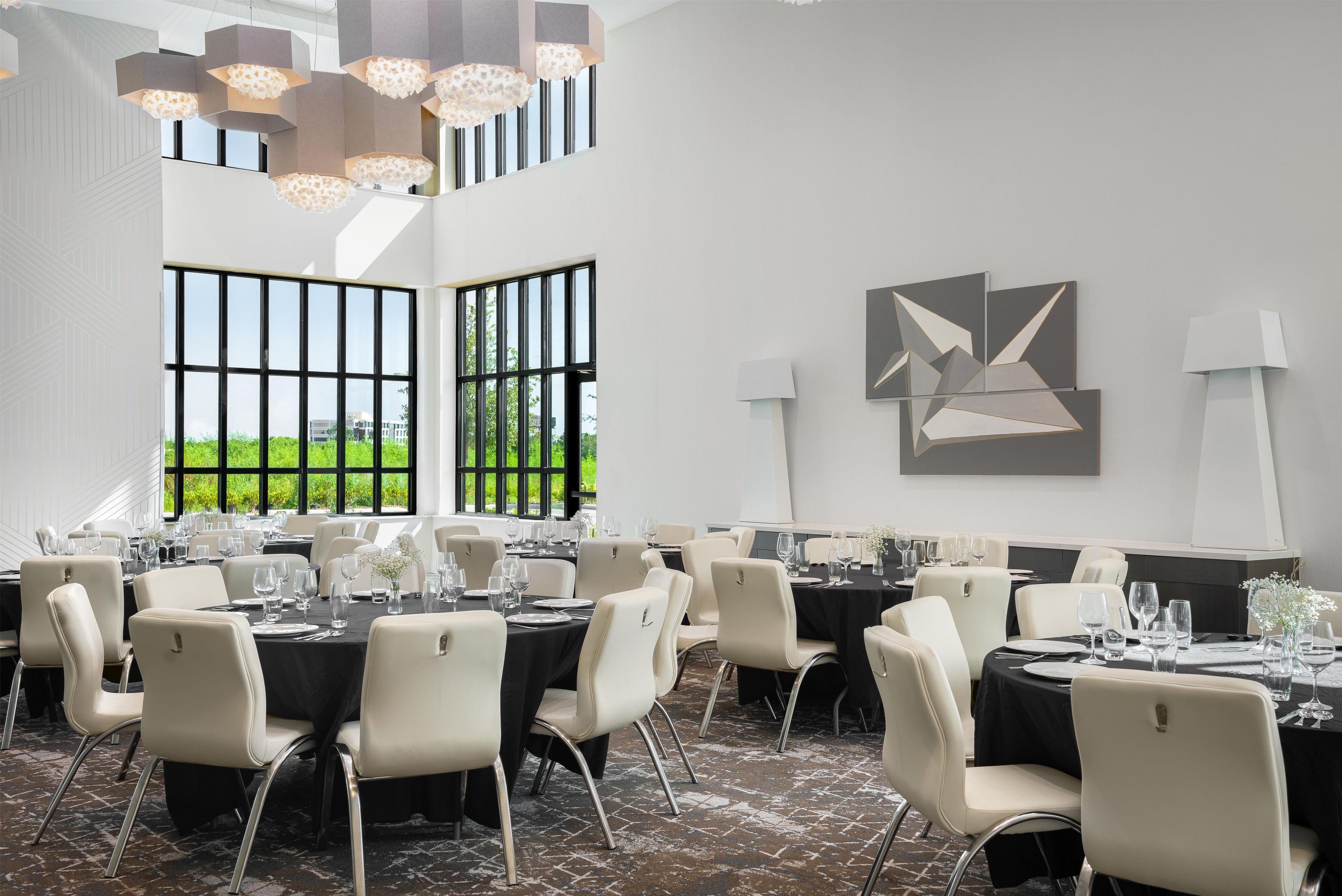 A conference room with multiple tables, chairs, and modern lighting fixtures.