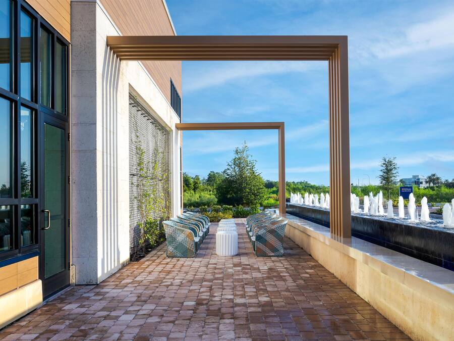 A hotel patio with a brick floor, outdoor seating, a water feature, and a view of the garden.
