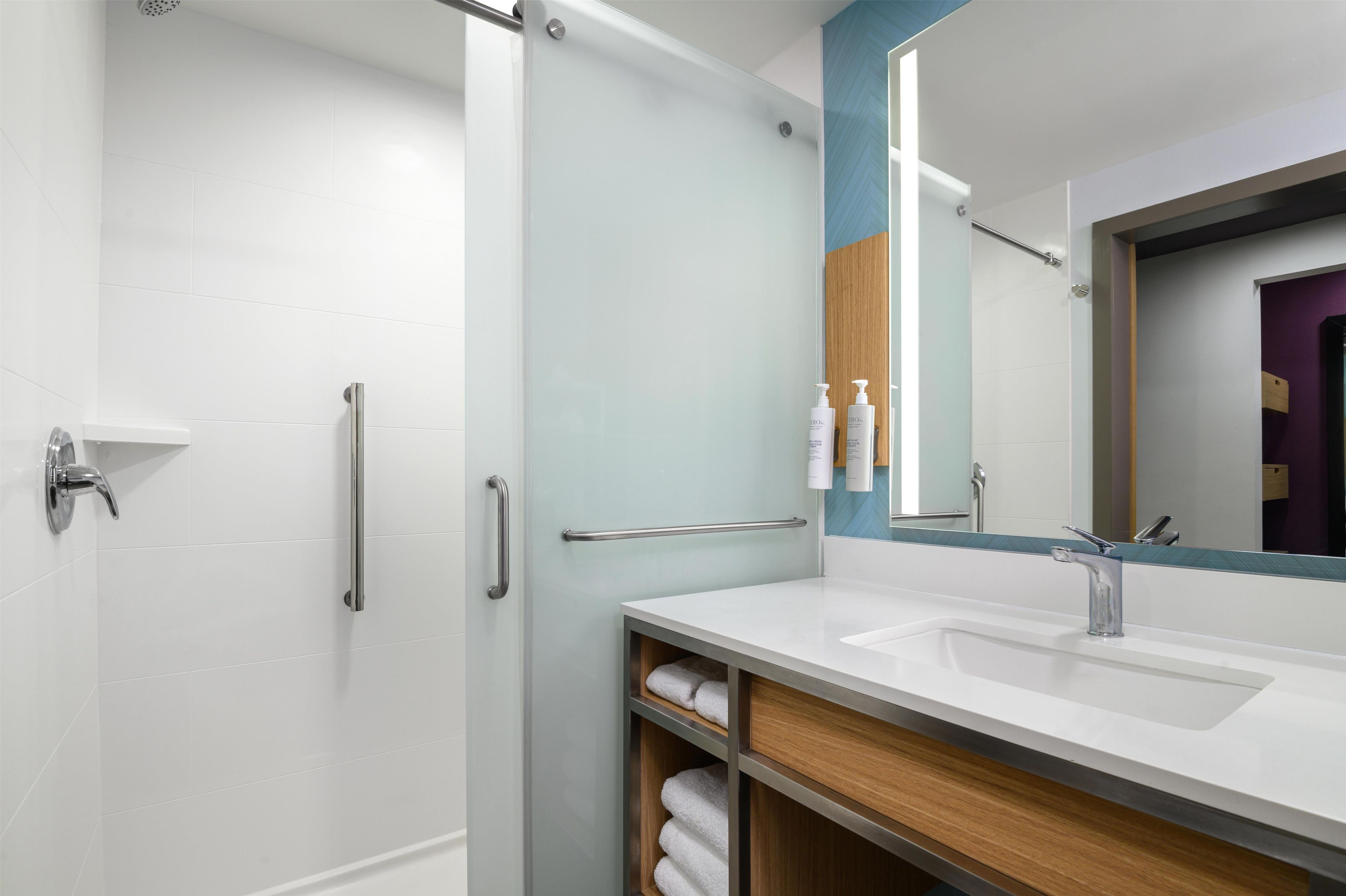 Une salle de bain moderne avec une douche à parois de verre, un meuble-lavabo avec miroir et un porte-serviettes.
