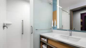 Une salle de bain moderne avec une douche à parois de verre, un meuble-lavabo avec miroir et un porte-serviettes.