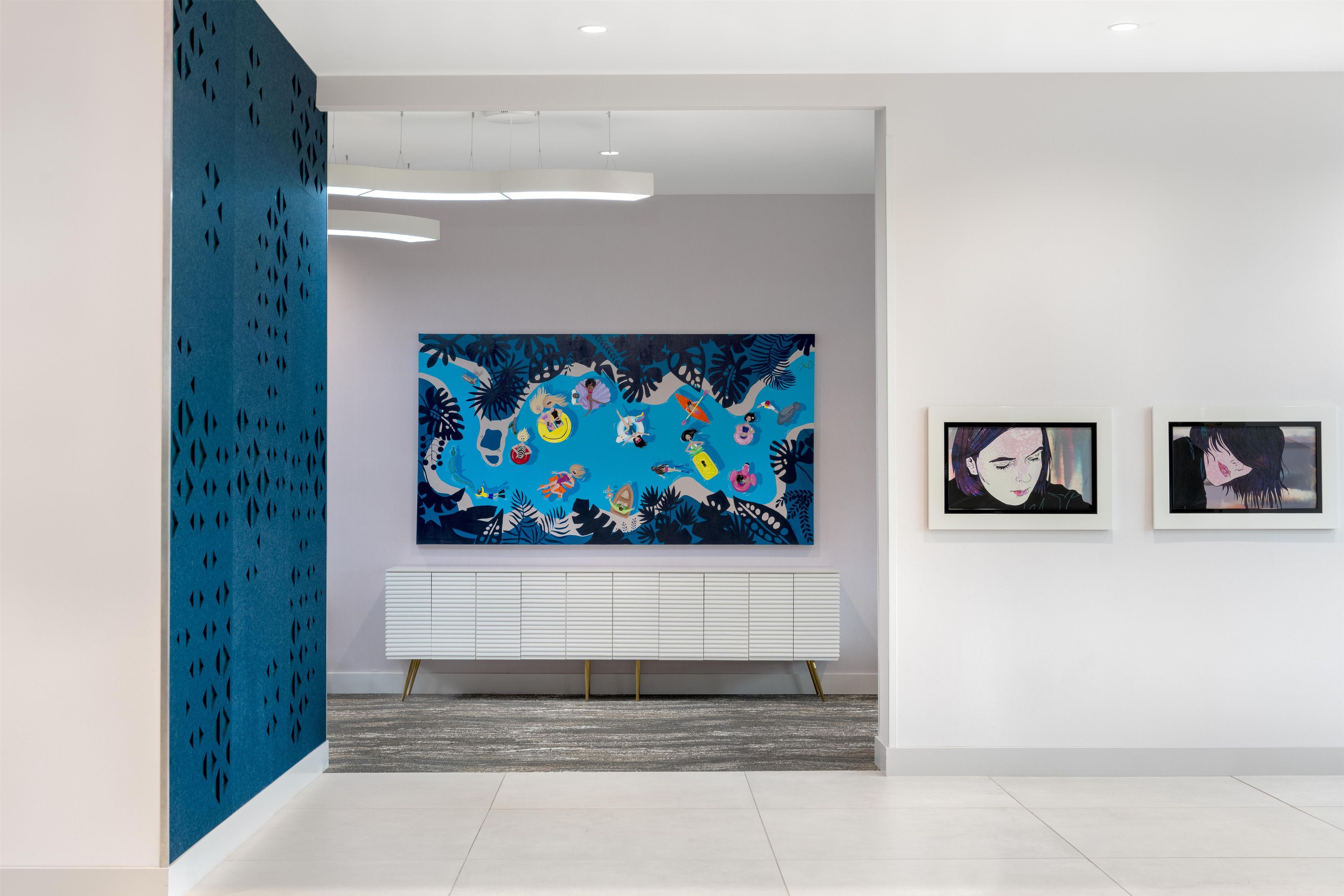 Eine moderne Kunstgalerie mit einem großen abstrakten Gemälde, einem weißen Konsolentisch und zwei gerahmten Kunstwerken an der Wand.