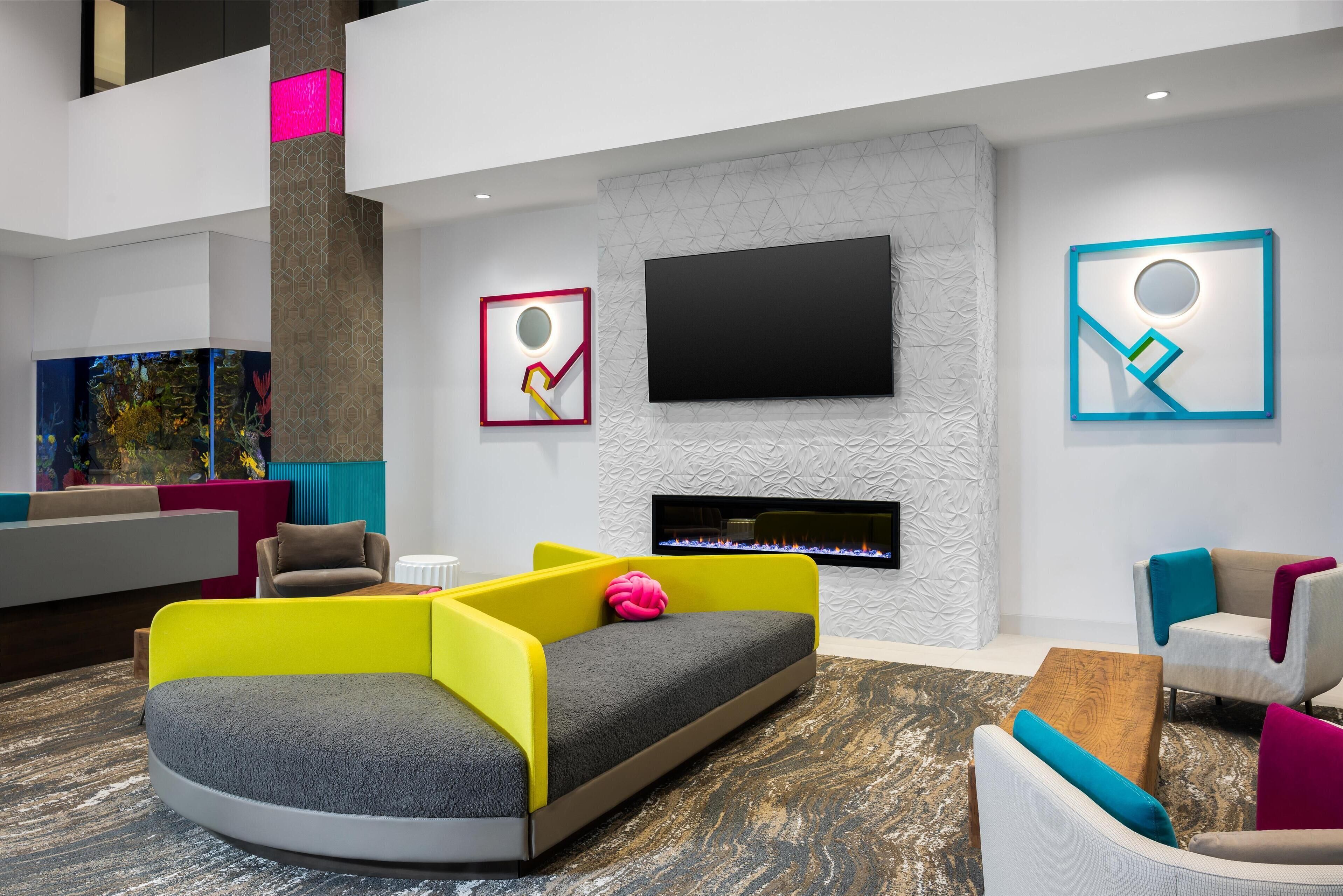 Una sala de estar moderna con un televisor de pantalla plana, una chimenea y asientos de colores.