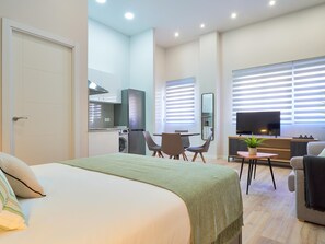 Une chambre d’hôtel moderne équipée d’un lit, d’un petit coin repas, d’une télévision et d’une kitchenette.