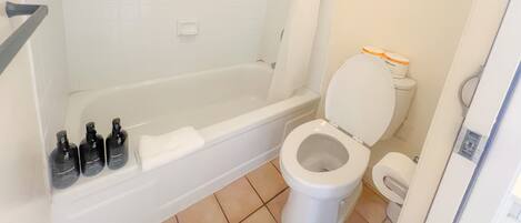 Un baño con bañera, inodoro y cortina de ducha.