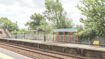 A train station platform with a shelter, a sign, and a fence.
