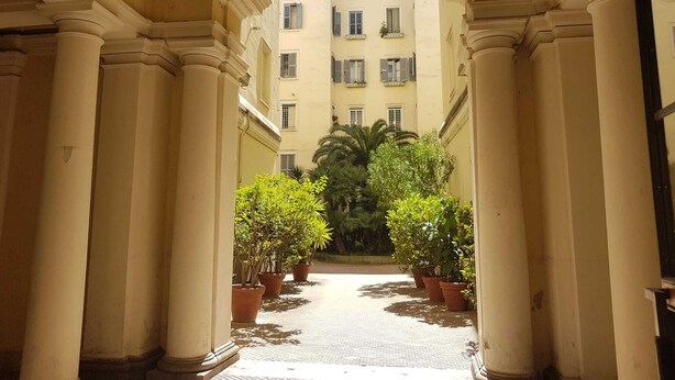 A corridor with columns, potted plants, and a building in the background. - Deluxe flat 2 bedrooms (Roma)