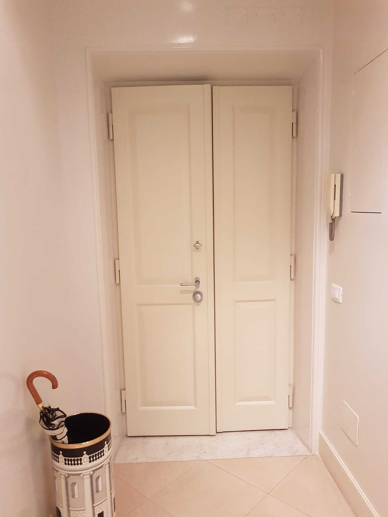 Ein Flur mit einer Doppeltür, einem kleinen Mülleimer und einem an der Wand befestigten Telefon.