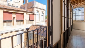 Een balkon met uitzicht op omliggende gebouwen, een houten plafond en een betegelde vloer.
