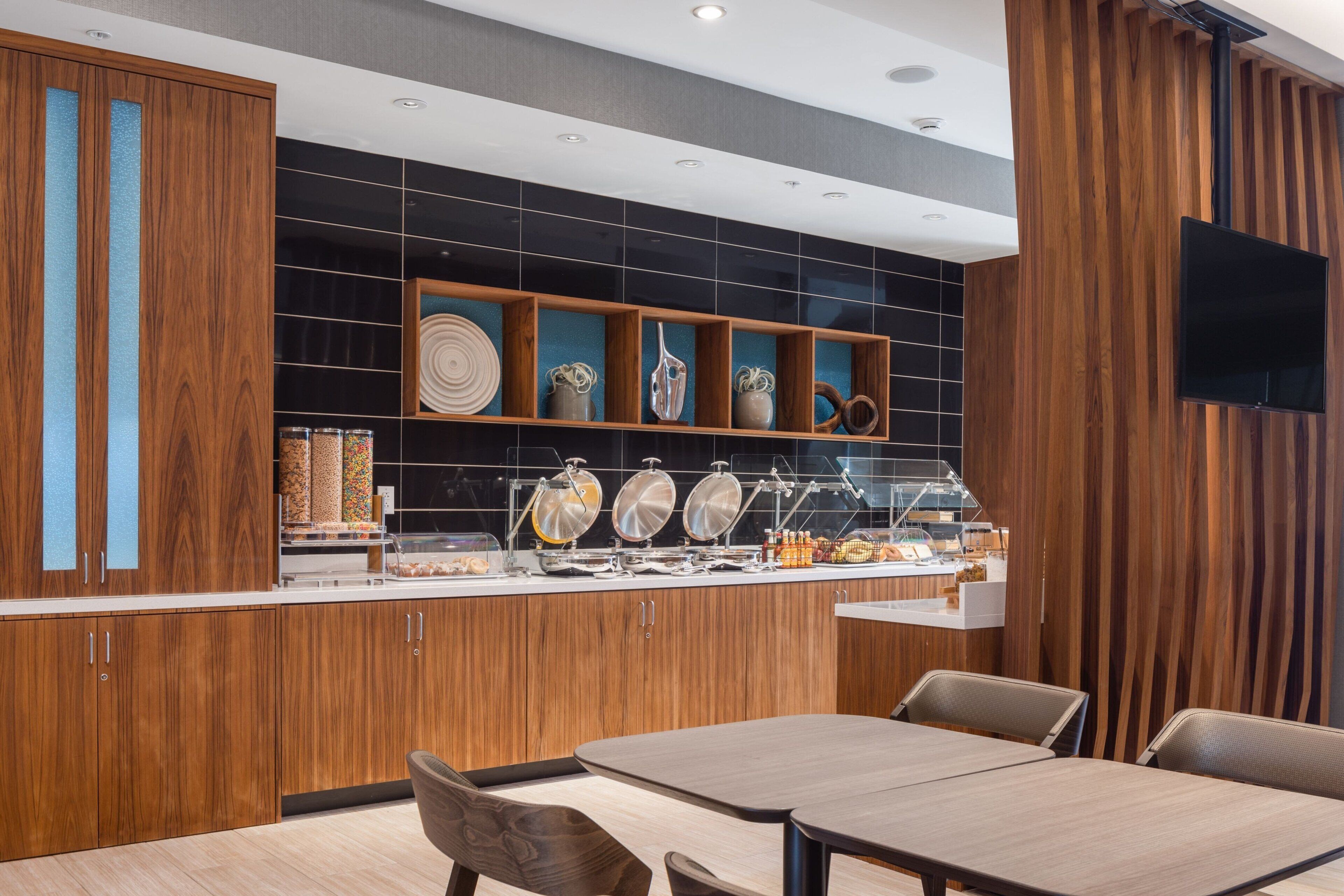 Una cocina moderna con armarios de madera, un mostrador tipo buffet y un televisor de pantalla plana en la pared.