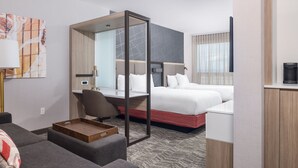 A modern hotel room with a bed, a desk, a chair, a sofa, and a coffee machine. - SpringHill Suites Tucson at The Bridges (Tucson)