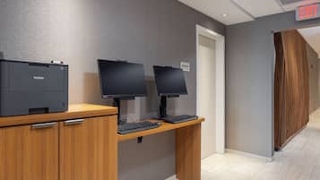 Un mostrador de recepción con una impresora Brother, dos monitores y un letrero que indica oficina de ingeniería.