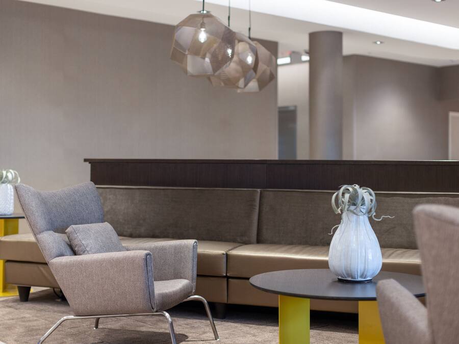 A modern lobby with a sofa, armchairs, and a table with a vase.