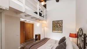 A bedroom with a bed, a wooden wardrobe, a bookshelf, a painting, and a lamp. - Saint Caterina House - Campo de Fiori (Rome)