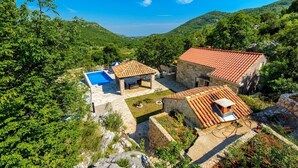 Une villa avec piscine, des bâtiments en pierre et un paysage montagneux en toile de fond.