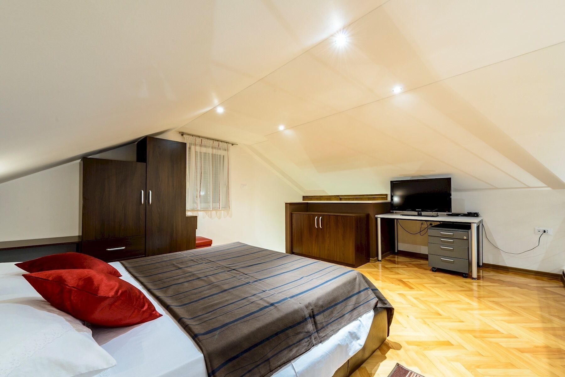 Une chambre à coucher avec un lit, un bureau avec une télévision et une armoire.