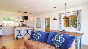 A modern kitchen with a central island, bar stools, and pendant lighting. - The Lookout (Sleat)