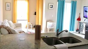 A kitchen with granite countertops, two sinks, and a dining area with a white table and chairs.