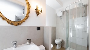 A bathroom with a large ornate mirror, a modern sink, a glass-enclosed shower, and a toilet. - Corso Vittorio - Campo de Fiori (Rome)