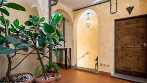An indoor courtyard with potted plants, a wooden door, and arched ceilings. - Cedro House in Trastevere (Rome)