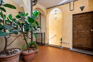 An indoor courtyard with potted plants, a wooden door, and arched ceilings. - Cedro House in Trastevere (Rome)
