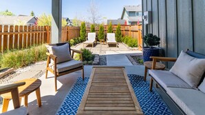 A patio with outdoor furniture, a wooden table, and a small rug.