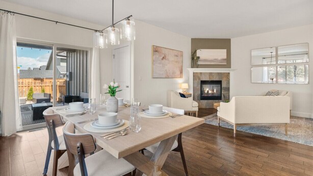 A modern living room with a fireplace, dining area with a table set for four, and a sofa.