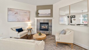 A living room with a fireplace, two sofas, a coffee table, and a large mirror.
