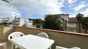 Un balcó amb taula i cadires blanques, amb vista a una zona residencial plena de cases i arbres.