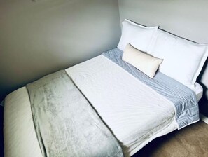 Comfortable bed with a white comforter and light duvet.