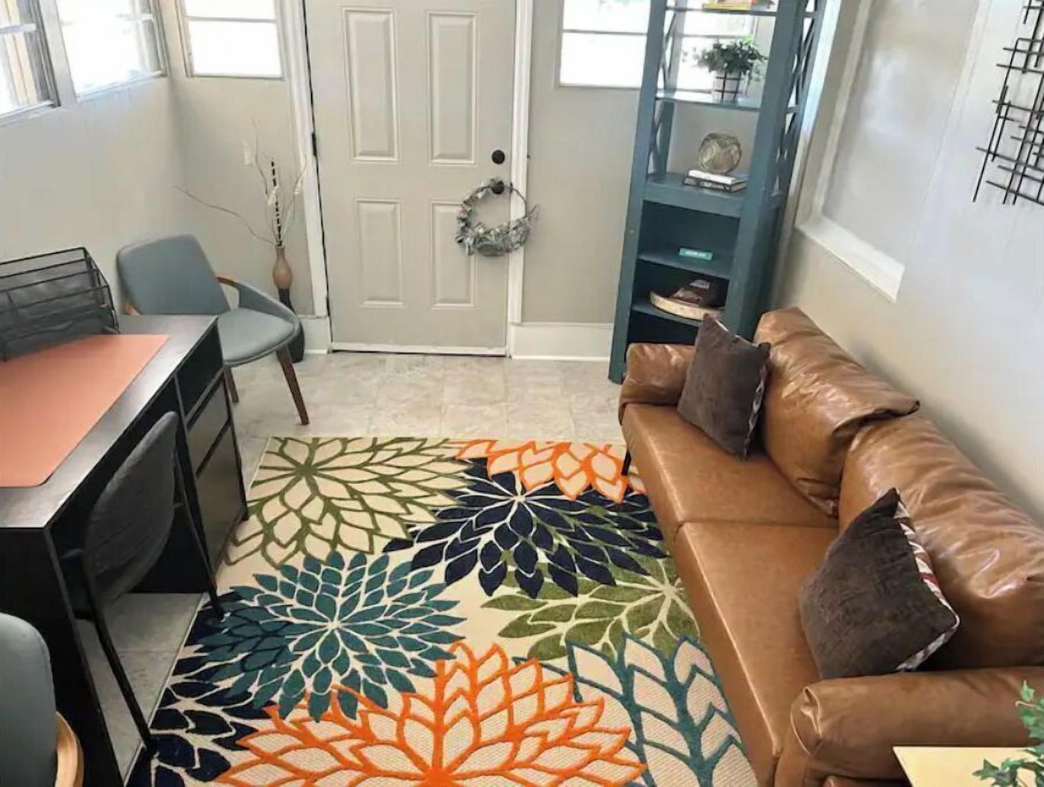 Una sala de estar con un sofá de cuero marrón, una mesita de centro y una alfombra estampada.