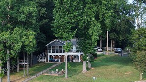 Un chalet au bord du lac, doté d’un quai, entouré d’arbres et d’une zone herbeuse.