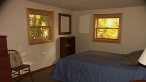 A bedroom with a bed, two windows, a chair, a dresser, and a mirror. - Wendell Cottage (Belgrade)
