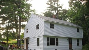 A two-story white house with a gabled roof, a front porch, and a small front yard. - Wendell Cottage (Belgrade)