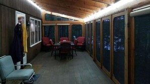 A covered outdoor area with a table and chairs, wooden walls, and large windows. - Serenity.. (Mount Vernon)