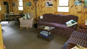 A cozy cabin interior with a wooden interior, a sofa, a dining table, and a small kitchenette. - Serenity.. (Mount Vernon)