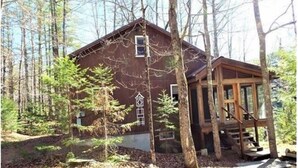 A rustic cabin with a wooden deck and a small porch, surrounded by trees. - Serenity.. (Mount Vernon)