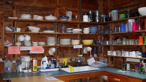 A kitchen with wooden shelves filled with dishes, a sink, and various kitchen items. - Haskell's Lodge on Long Pond! (Belgrade)